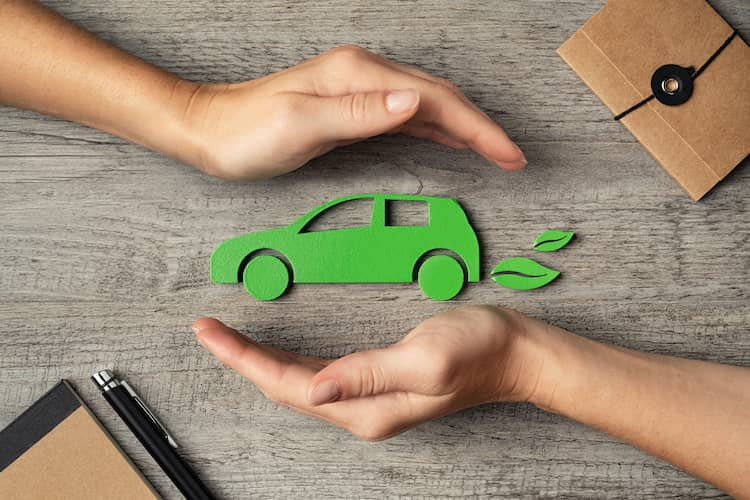 Zwei Hände umfassen ein grünes Elektroauto