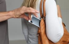 Hand zieht Handy aus Handtasche